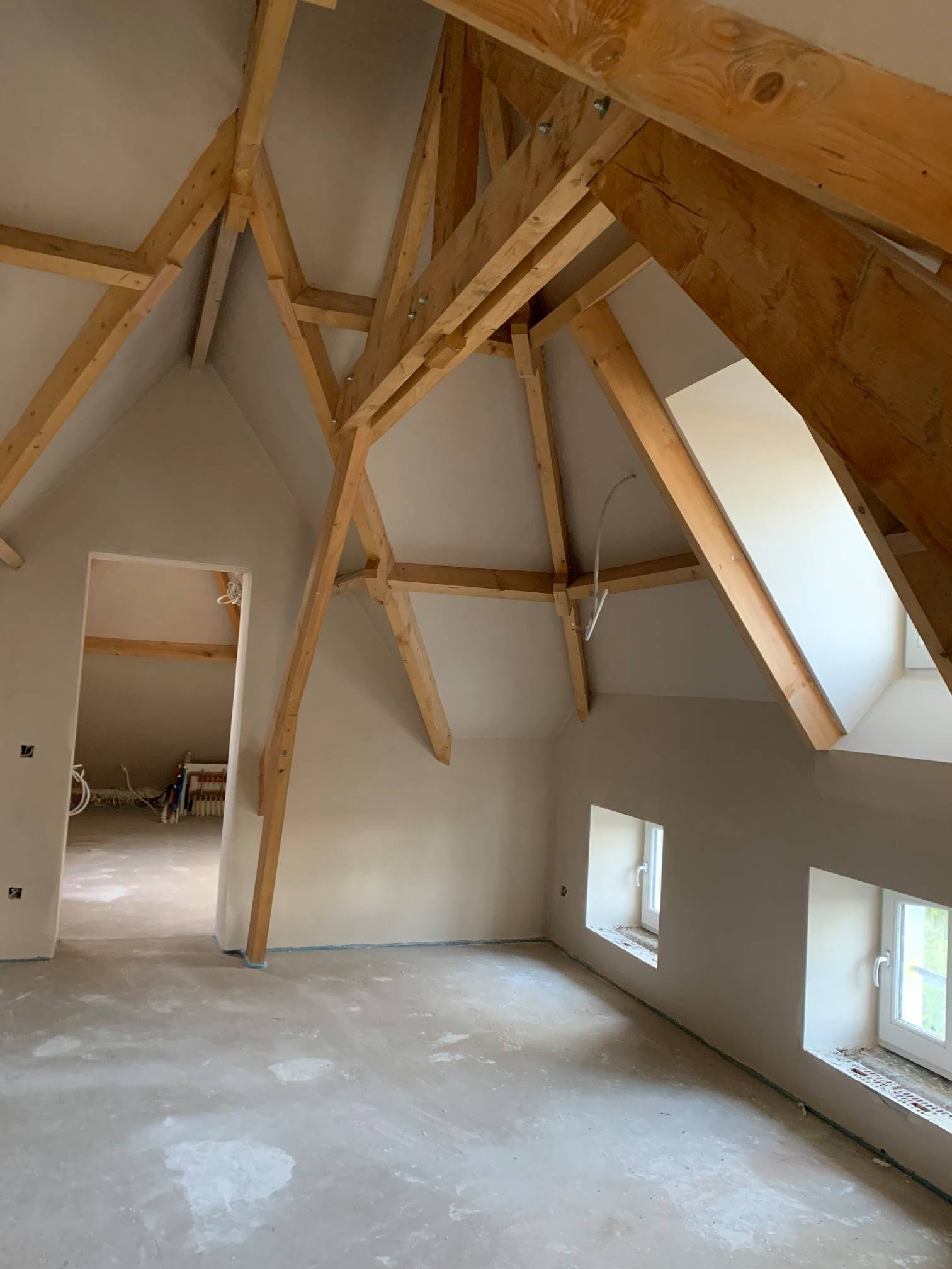 Zolderruimte met zichtbare houten dakstructuur en afgewerkte pleisterwerken